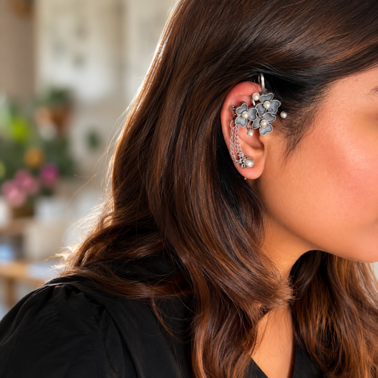 Woman wearing oxidised floral chain ear cuffs with pearl accents and antique silver finish, showcasing trendy no-piercing oxidised ear cuffs for women.